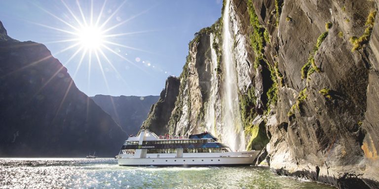 cruise ship approaches waterfall in Milford Sound, Fiordland